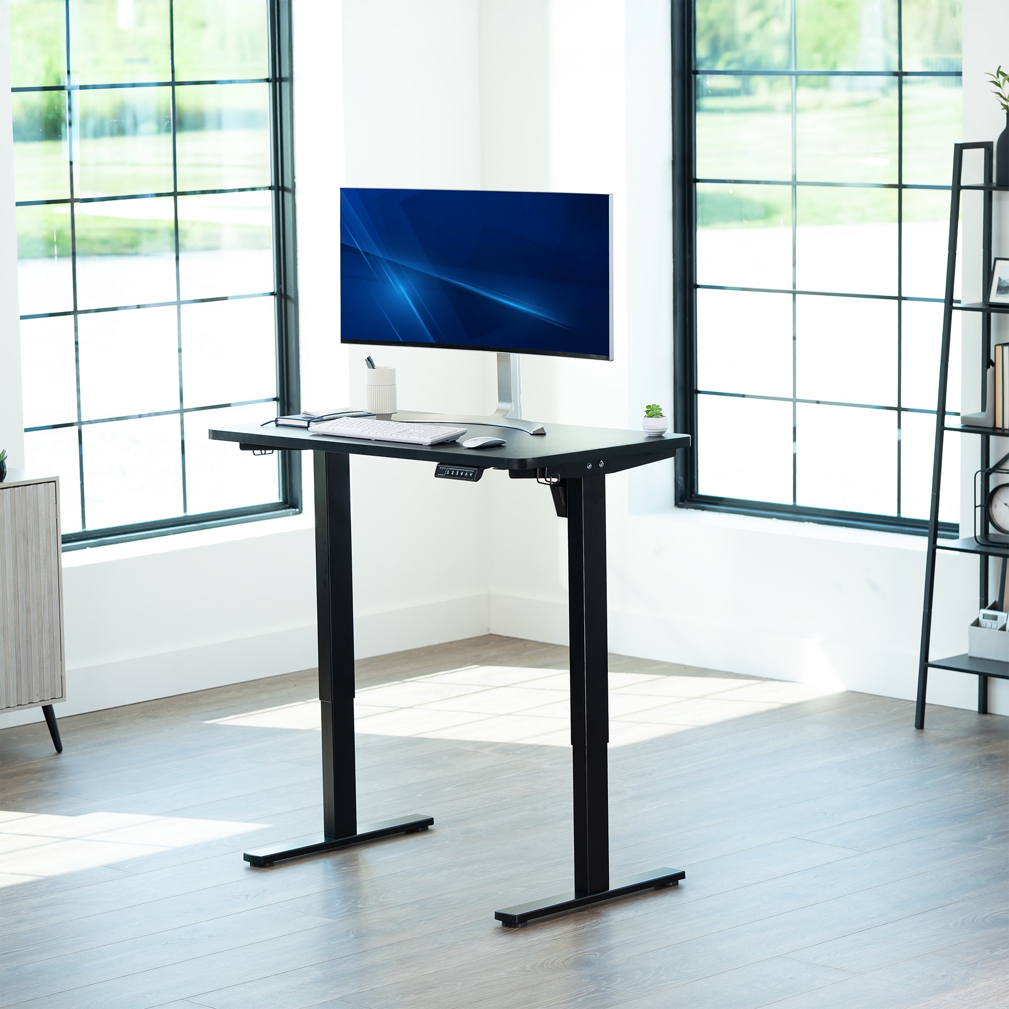 Black, height adjustable, electric, sit to stand desk in office setting.