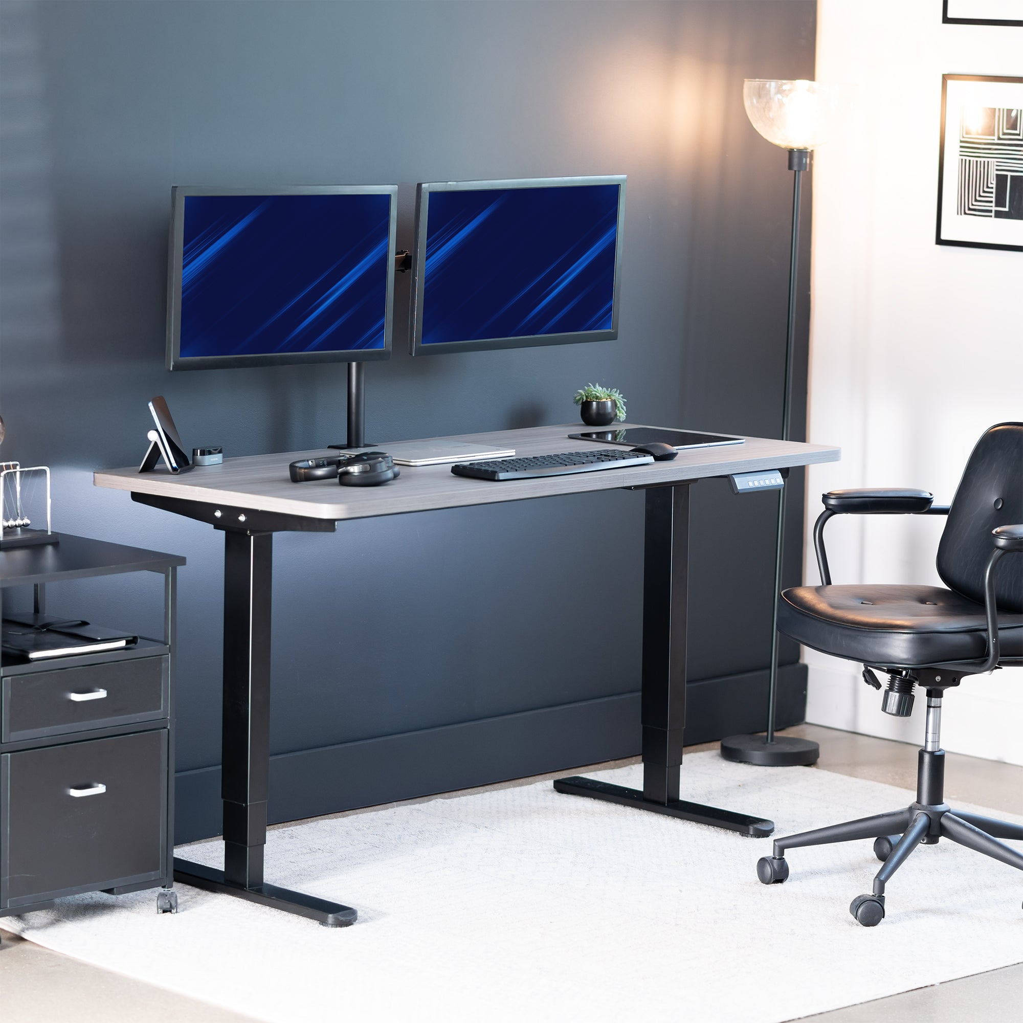 Modern office setup with a standing desk, computer monitors, and chair.