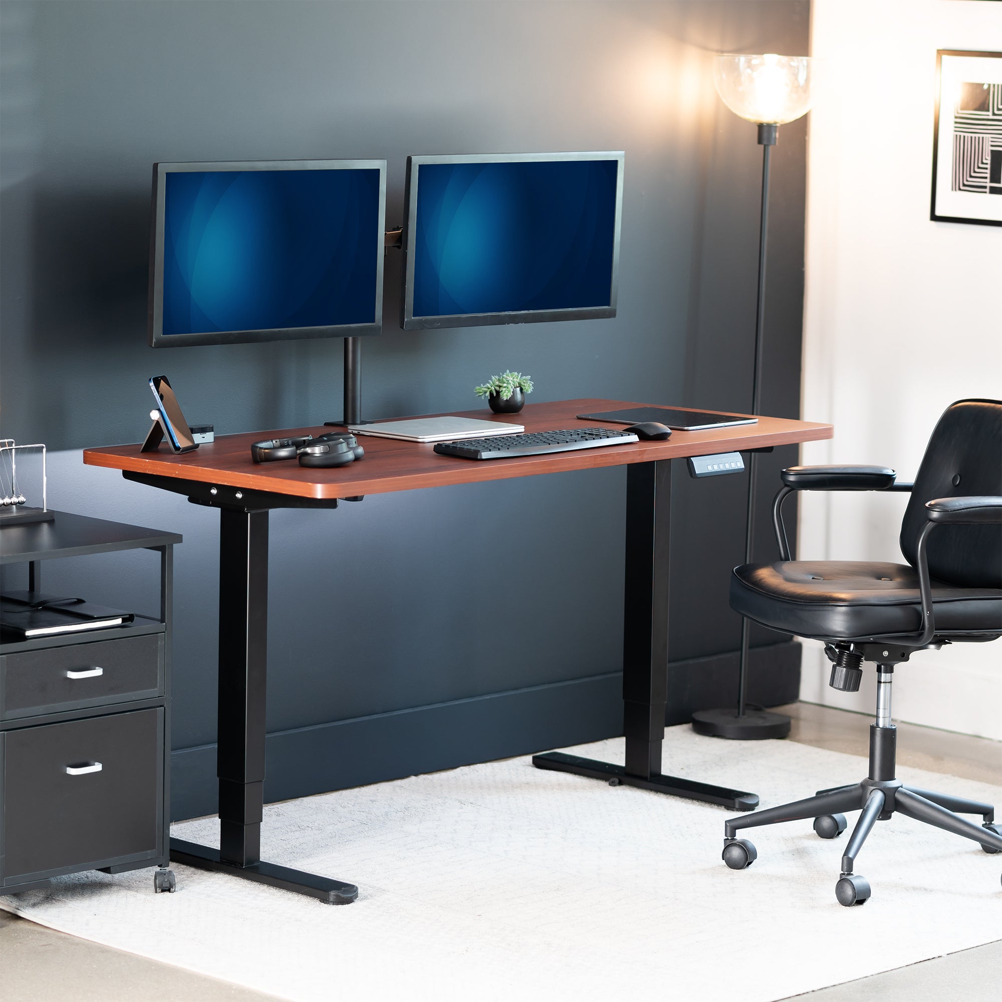 Modern office setup with a standing desk, dual monitors, and a chair.