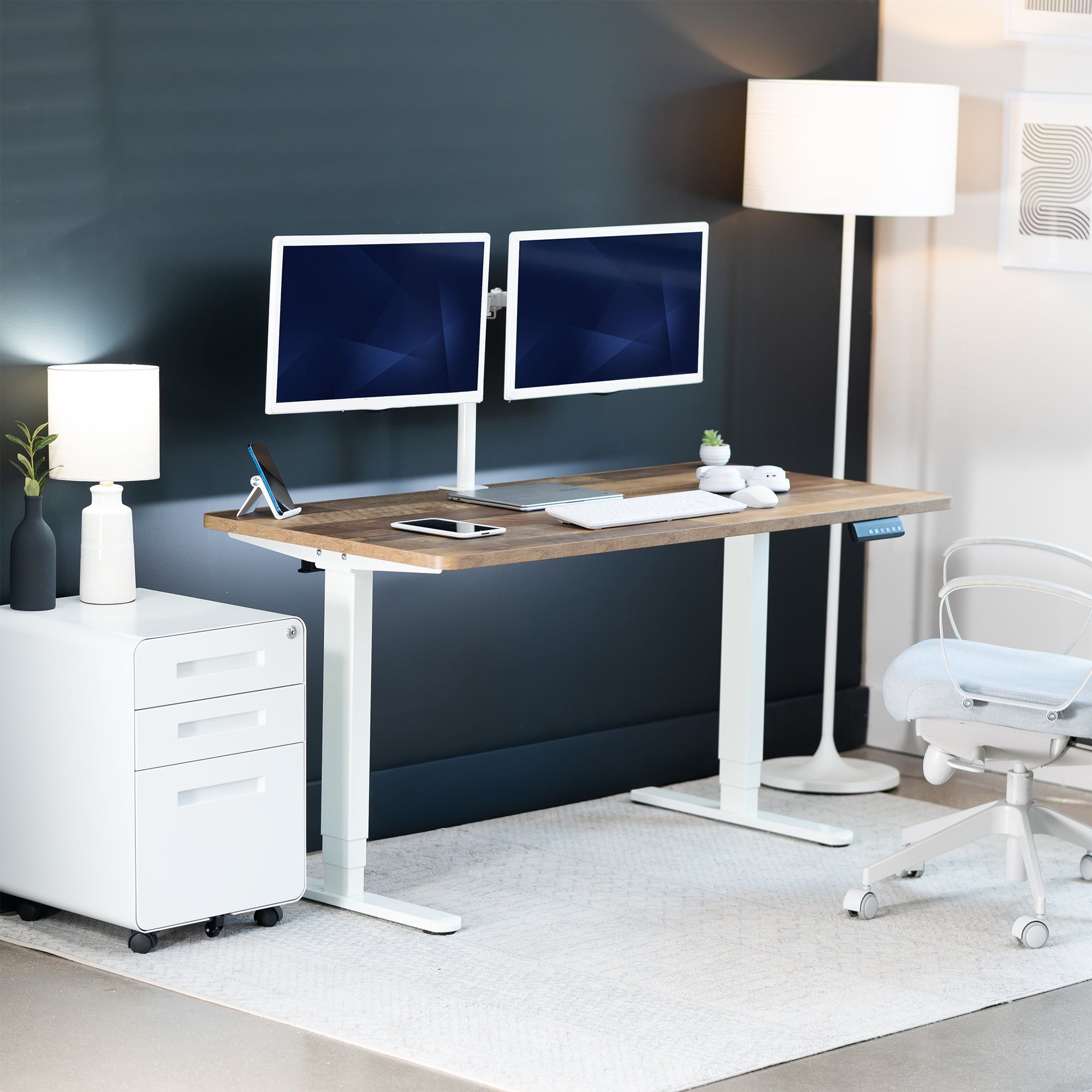Modern home office setup with a standing desk, computer monitors, and office chair.