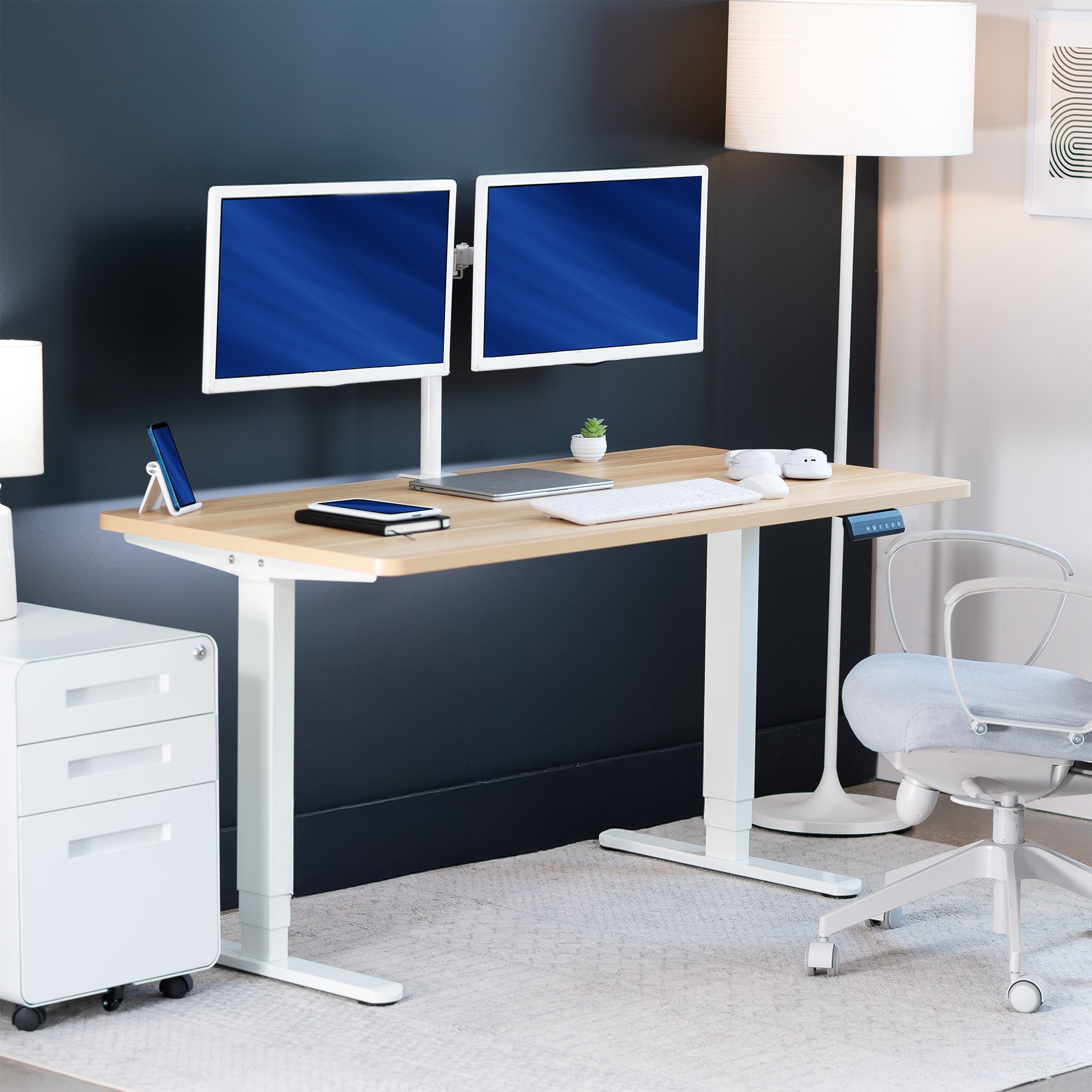 Modern office setup with a standing desk, computer monitors, and office chair.