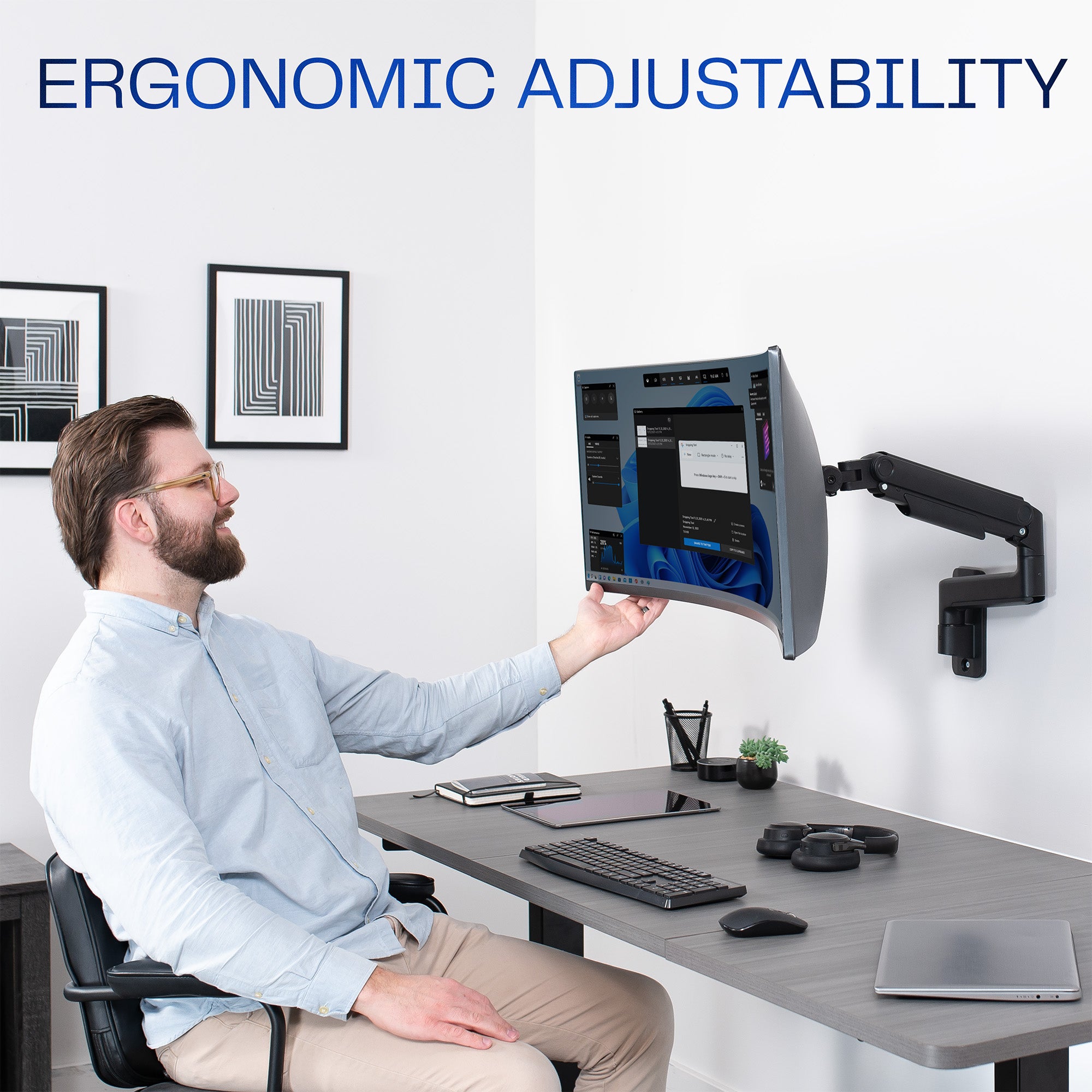 A single ultrawide computer monitor attached to a pneumatic arm wall mount with text on adjustability.