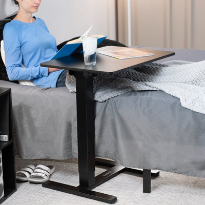 Sturdy steel mobile overbed table with electric height adjustment.