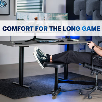 Person sitting at a desk with feet up on a footrest wearing black shoes and pants, in an office setting.