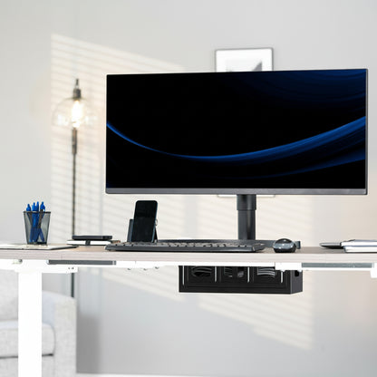 Modern office desk setup with a computer monitor, keyboard, under desk cable management box, and office supplies.