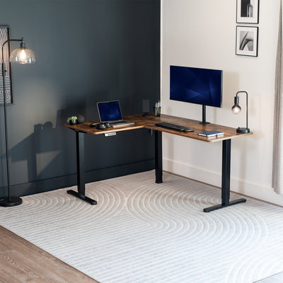 Modern L-shaped desk with computer setup in a room with a dark wall and light floor.