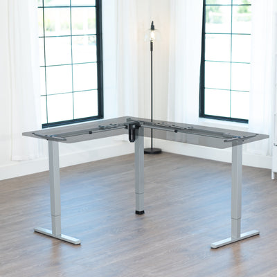 Modern adjustable, gray desk frame in a bright room with large windows