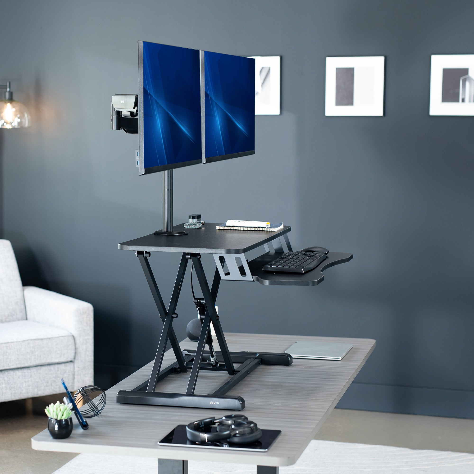 Height adjustable desk riser with articulating mechanical dual monitor mount.