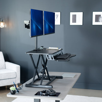 Height adjustable desk riser with articulating mechanical dual monitor mount.