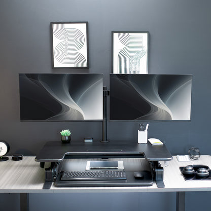 Height adjustable desk riser with articulating dual monitor mount.