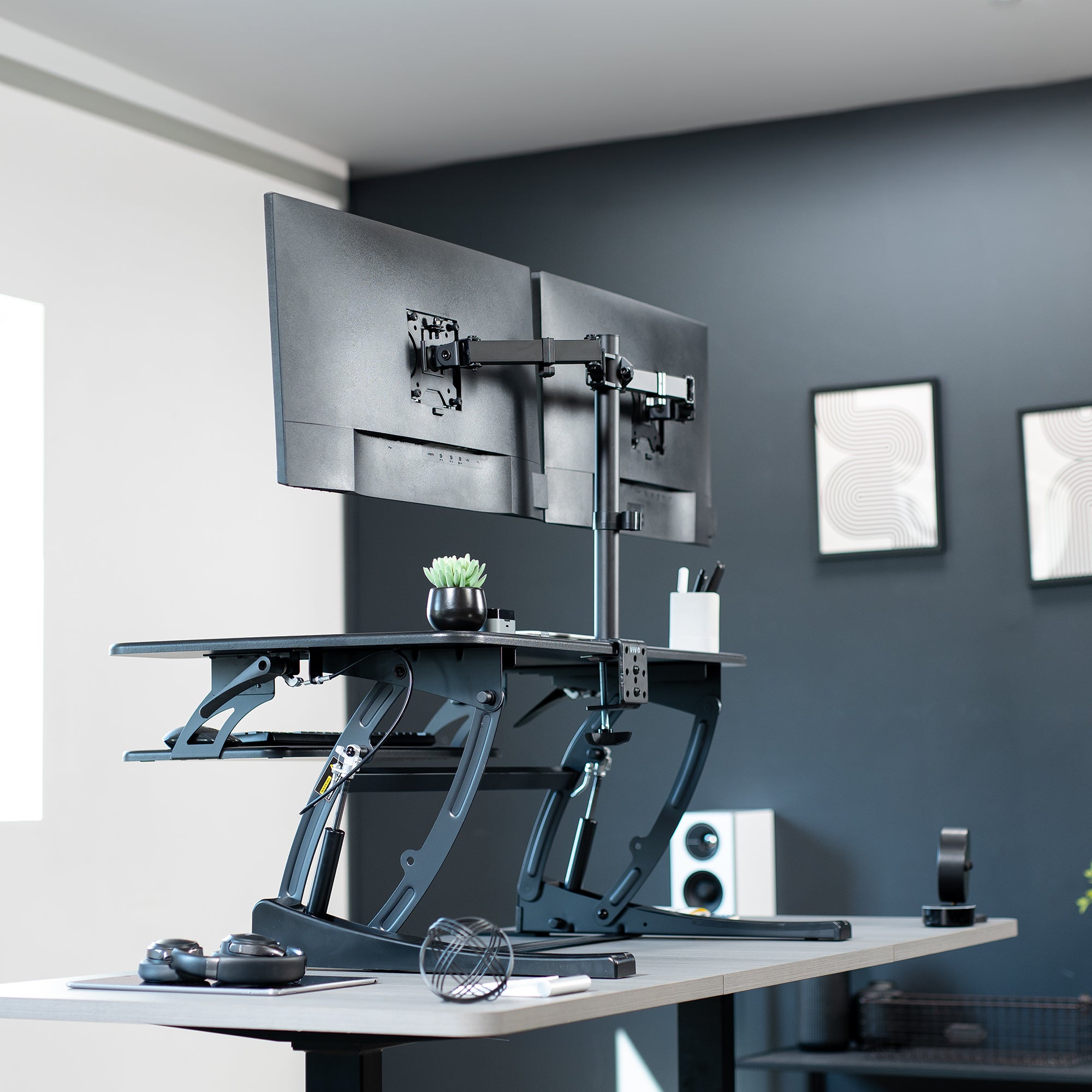 Height adjustable desk riser with articulating dual monitor mount.