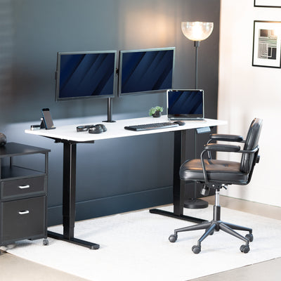 Modern office desk setup with two monitors, a laptop, and a chair in a well-lit room.