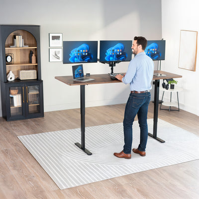 Man standing at the 2E Series - 83" x 30" Electric Desk with Touch Screen Memory Controller