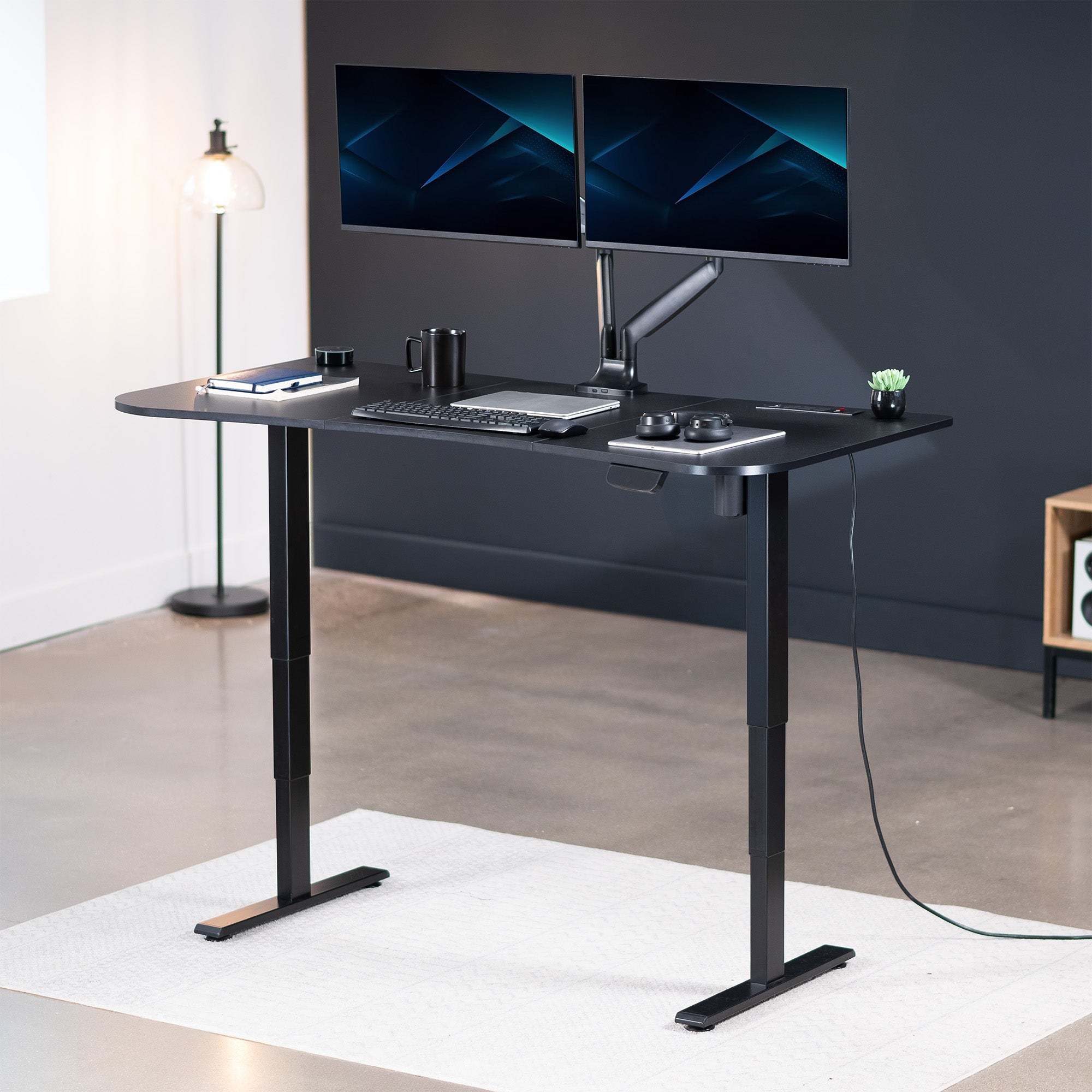 63” x 32” Electric Height Adjustable Stand Up Desk in Modern Office Space. Features a built-in power strip.