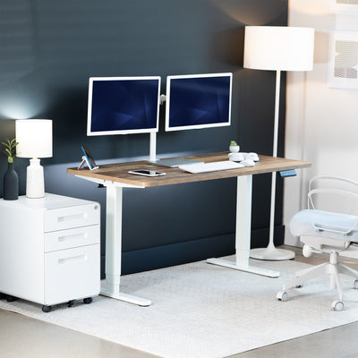 Modern home office setup with a standing desk, computer monitors, and office chair.