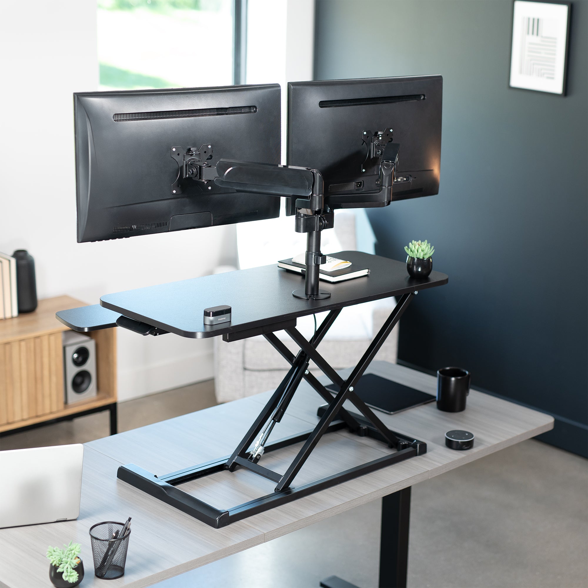 36 inch height adjustable desk riser with articulating pneumatic dual monitor mount.