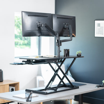 42 inch height adjustable desk riser with articulating pneumatic dual monitor mount.