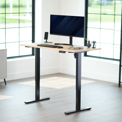 Modern office setup with a standing desk, computer monitor, keyboard, and mouse in a bright room.