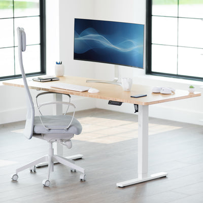 Modern office desk with a computer monitor, chair, and office supplies in a bright room.