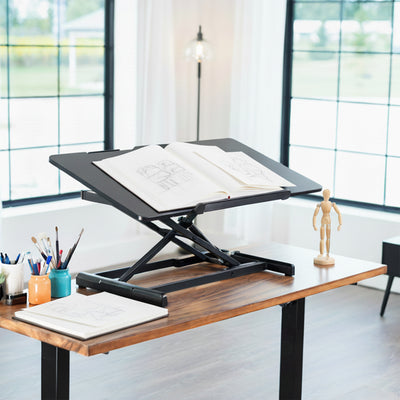 Adjustable standing desk in a bright room with large windows