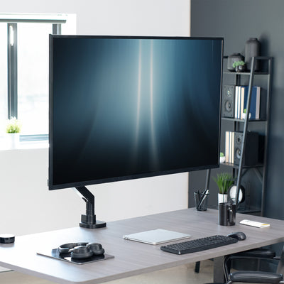 Modern office setup with a large monitor on a desk, keyboard, and mouse.