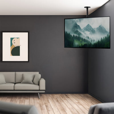 Modern living room with a gray sofa, framed artwork, and a mountain-themed TV screen.