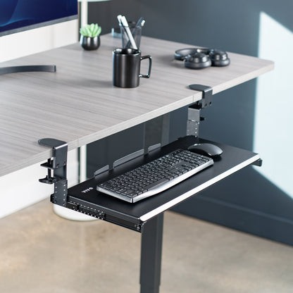 Under desk sliding ergonomic keyboard tray with room for a mouse on desk in home office setting. 