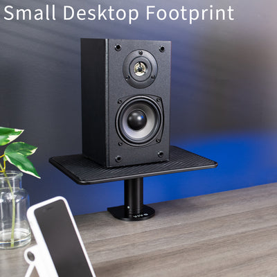 Black speaker on a stand with a smartphone and plant on a table, against a blue gradient background.