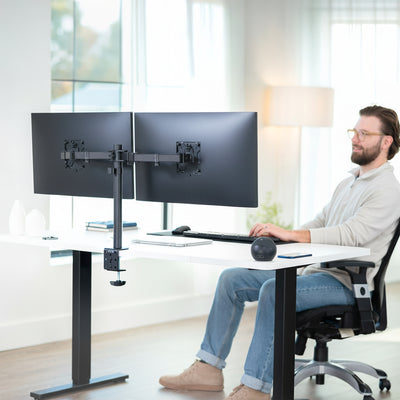 Person using a dual monitor desk mount in home office setting