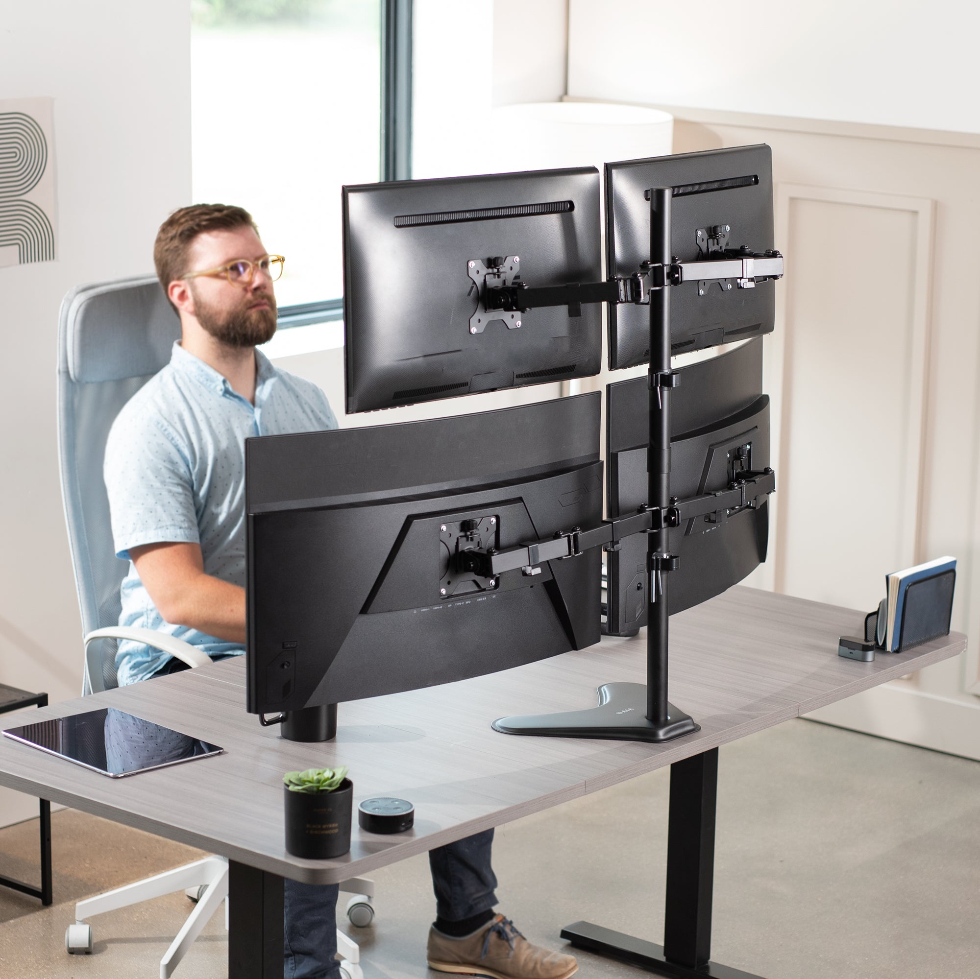 Quad Monitor Desk Stand holds 4 screens for work efficiency at your office desk. Features a freestanding base.