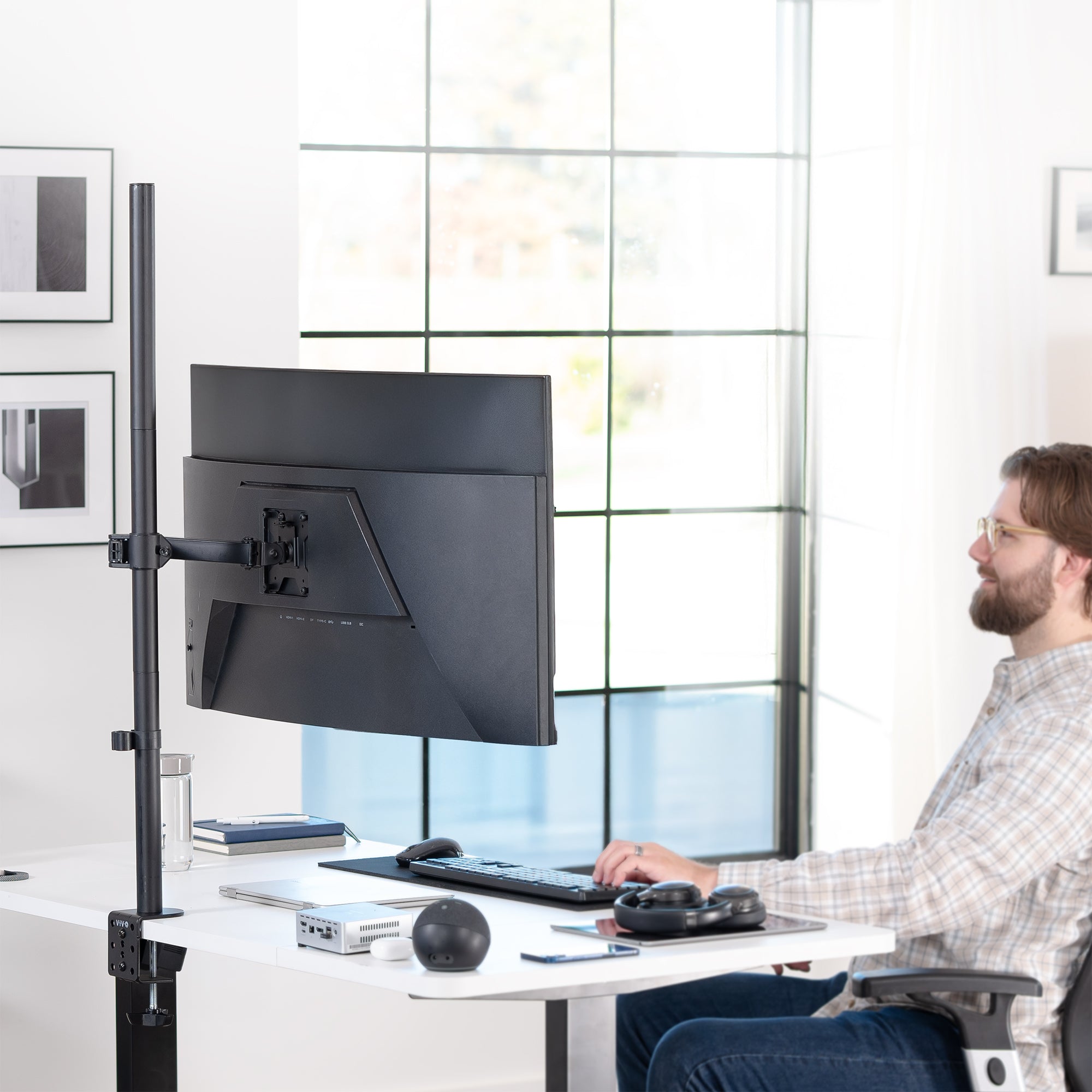 Person using a computer setup with a monitor on an adjustable extra tall monitor stand in a modern office.
