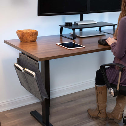 A woman working in an office space while utilizing a side pocket to save desk space.