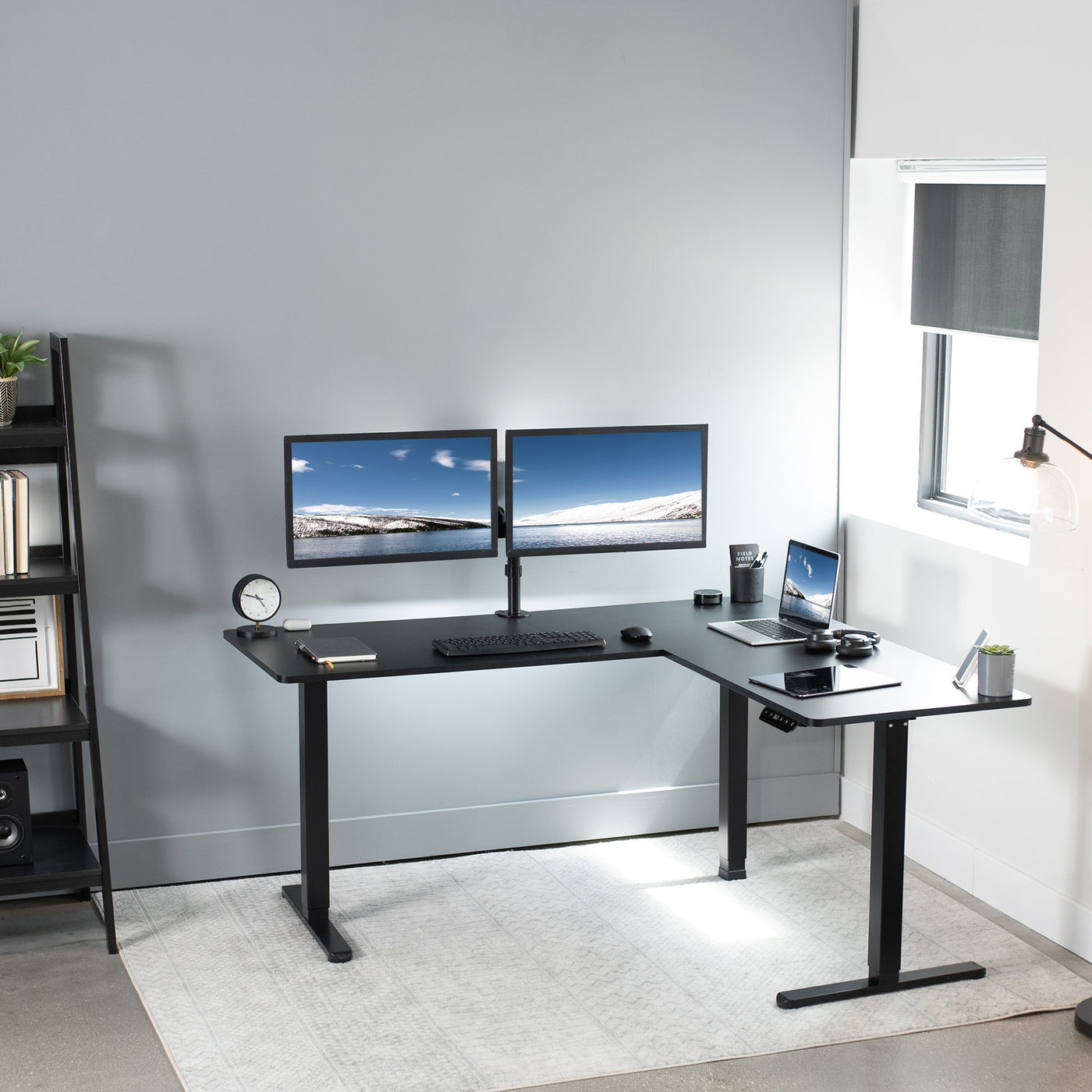Modern working office with an ergonomic sit to stand L-shape desk by a window.