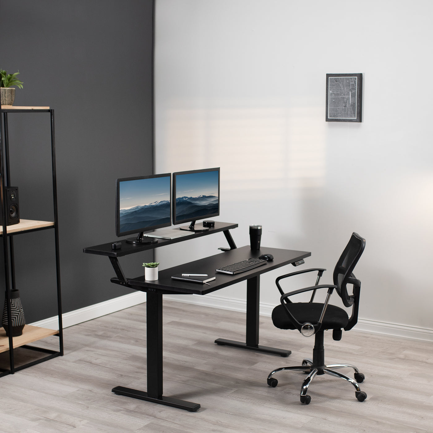 Still modern office space with electric desk chair and two monitors elevated on an ergonomic split desk frame.