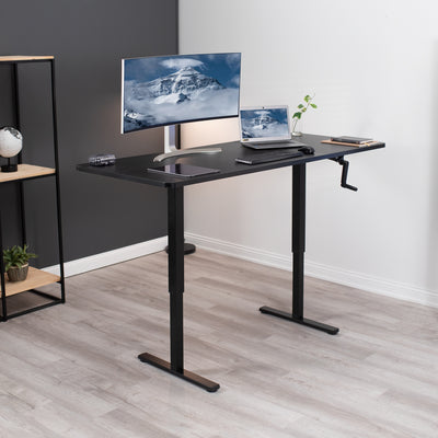 Side hand crank desk with a large monitor, keyboard, laptop, and tablet. 