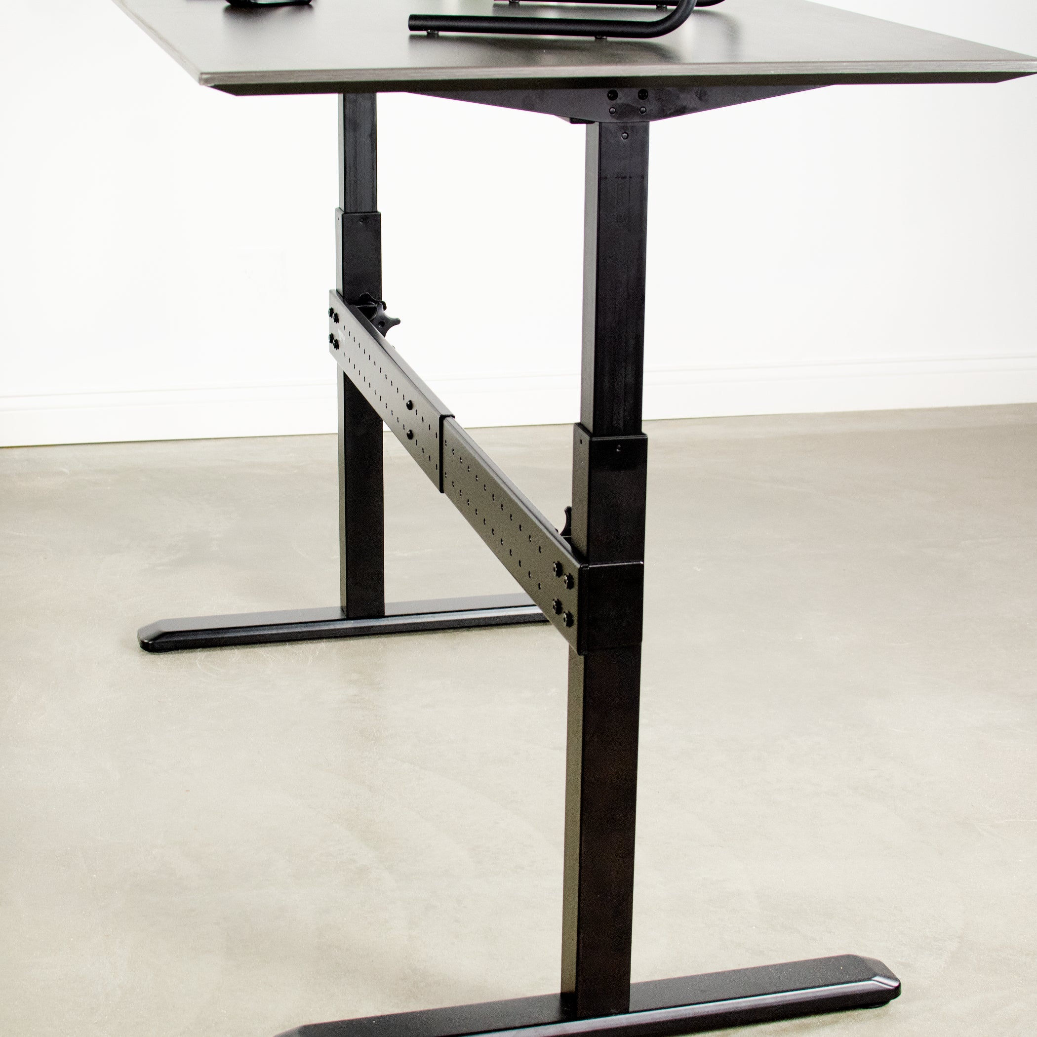 Black support clamp on bar with black frame desk.