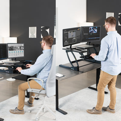 A man working while sitting and standing in an office with a sit-to-stand desk converter.