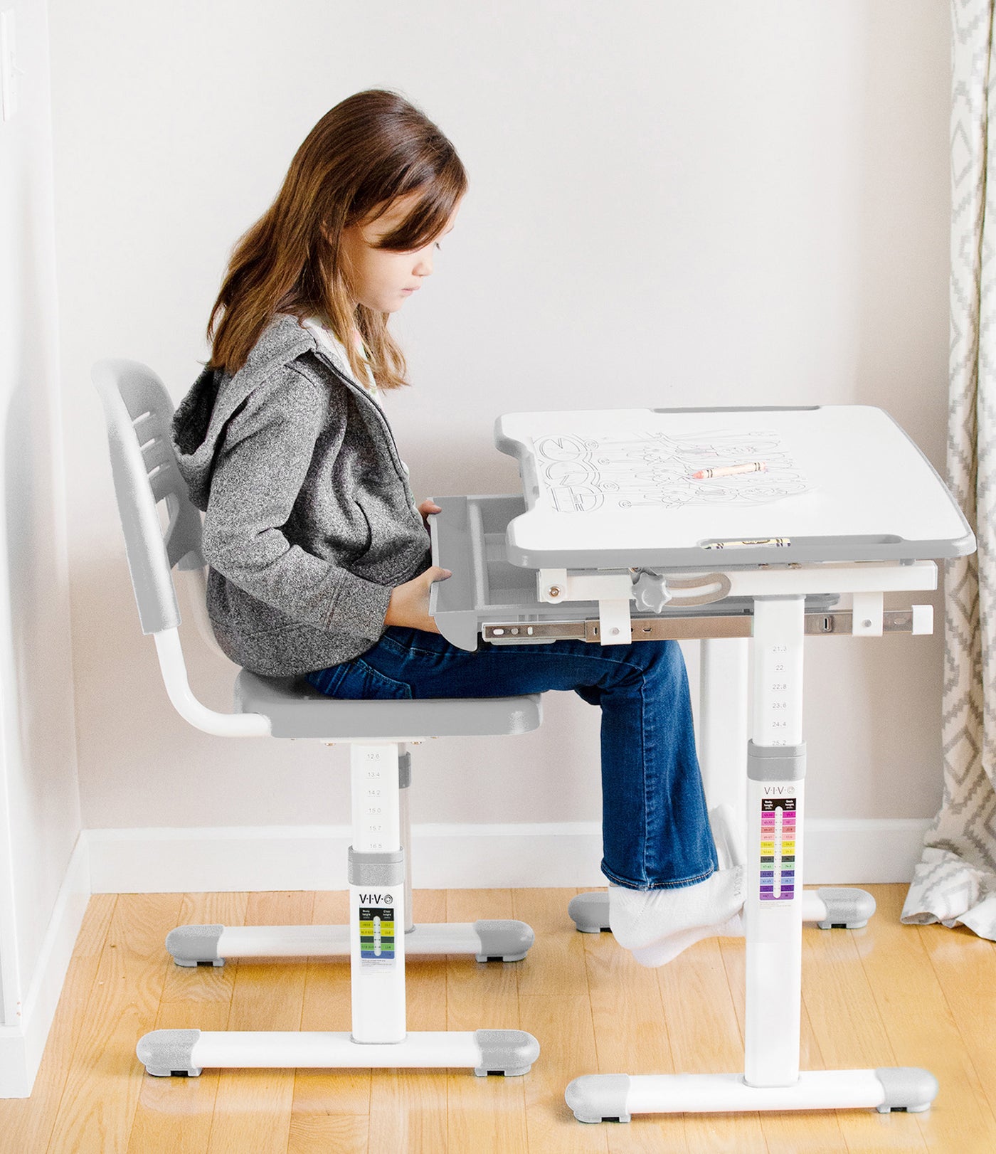 A girl working at a height-adjustable ergonomic kid's desk.