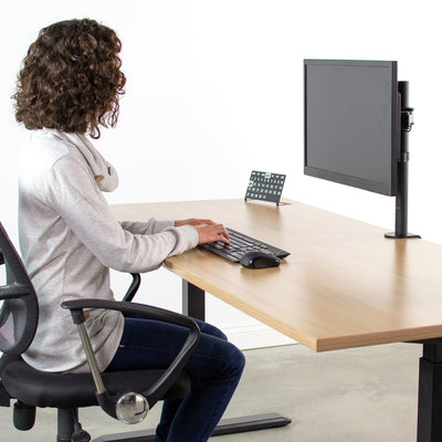 Woman typing at an ergonomic monitor set up.