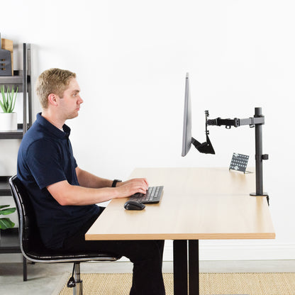 Office work desk with a man working from an elevated ASUS monitor mounted with a VESA plate adapter.