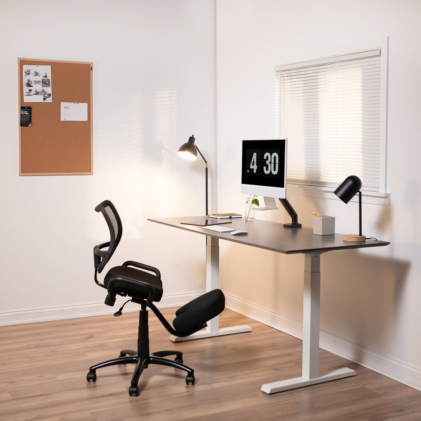 Modern office with kneeling chair and M1 MAC mounted to a desktop for ergonomic viewing angles.