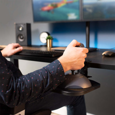 A person at an ergonomic desk using a joystick on a clamp on a mouse pad.