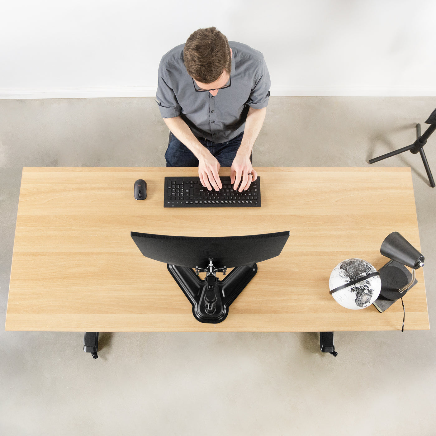 A person working at an ergonomic desk with a mounted Viotek monitor screen