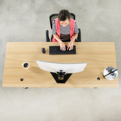 A woman working at a large office desk with a Samsung series CF591 attached to a mount through a specially designed bracket.