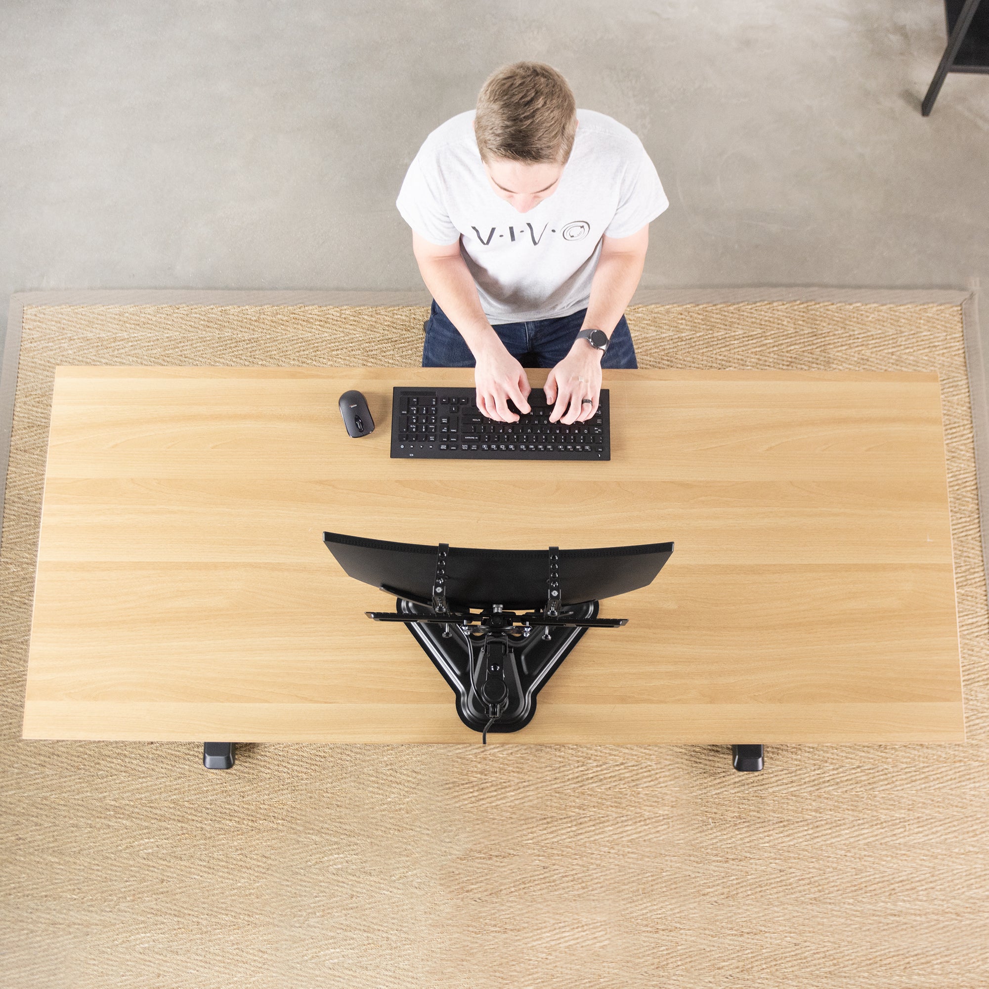 Man working from a sit to stand ergonomic desk from vivo with a universal VESA adapter bracket supporting monitor.