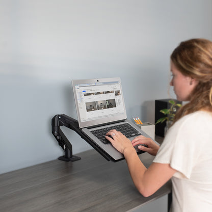 A woman working from a laptop on a laptop tray.