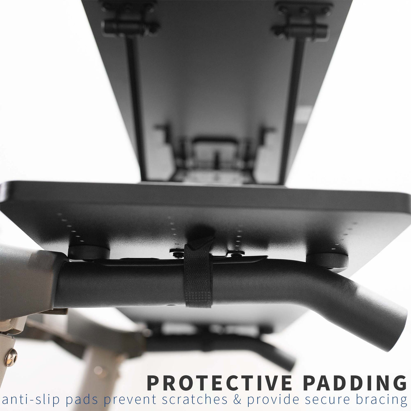 Protective padding and secure mounting straps of a height-adjustable treadmill desk.