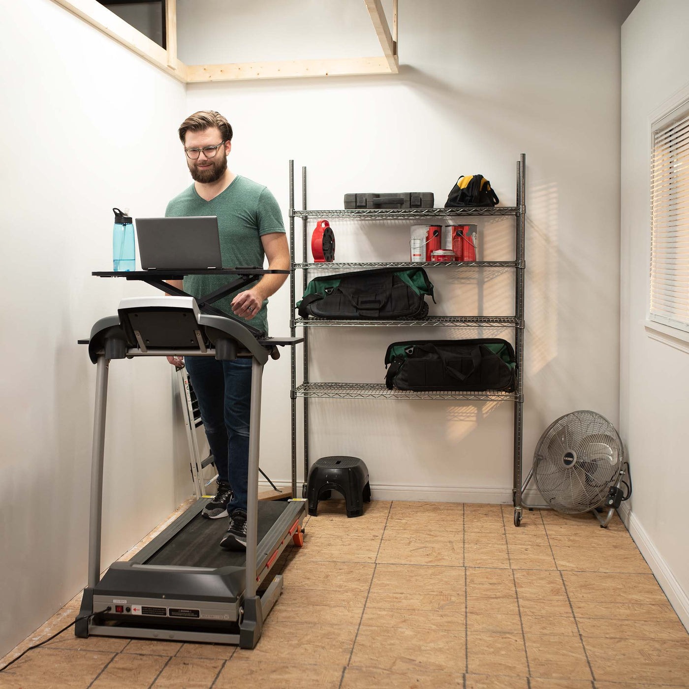 A man walking on a treadmill while working from his laptop.