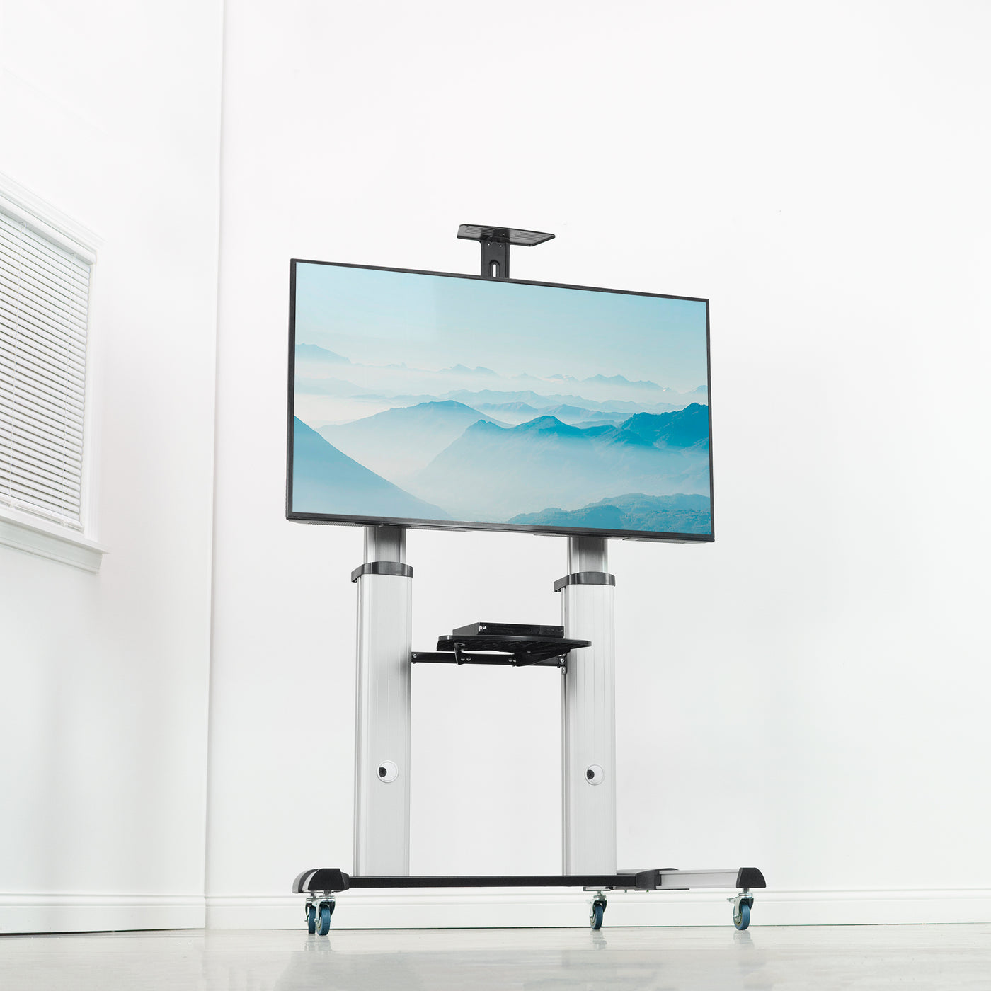 Large TV displayed on a modern TV cart in an empty white room.