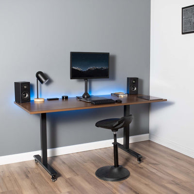 Black monitor mount stand on a sit-to-stand office desk.